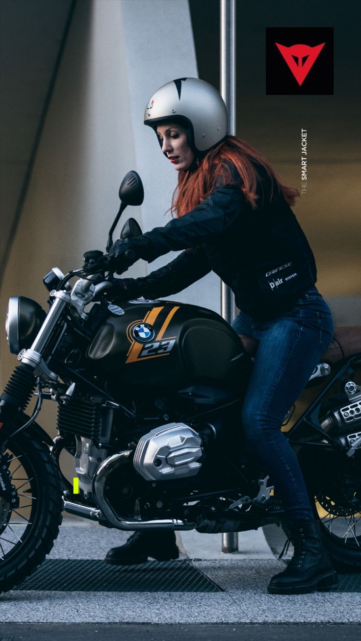 a woman in black jacket and helmet sitting on motorcycle