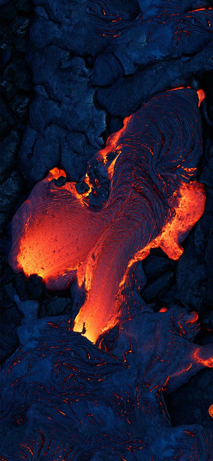 an aerial view of lava in the ocean with red and orange light coming from it