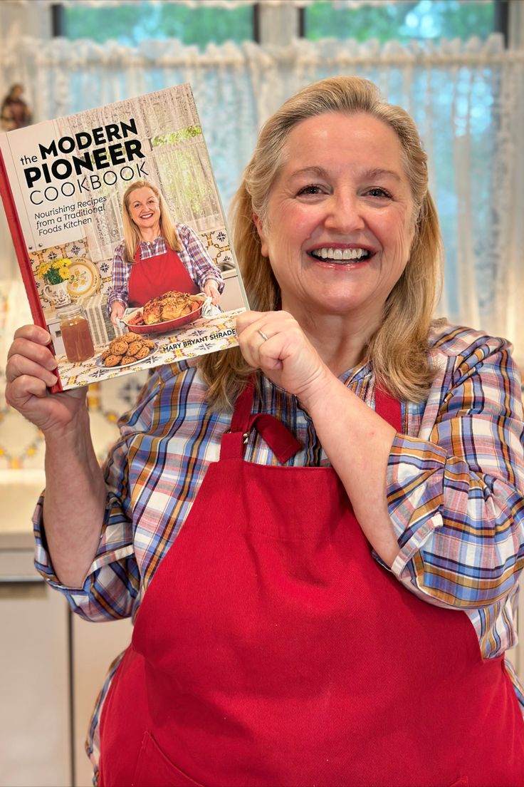 a woman in an apron holding up a cookbook