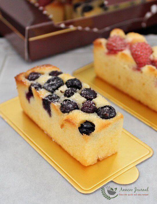 two slices of cake with berries on them sitting on trays next to each other