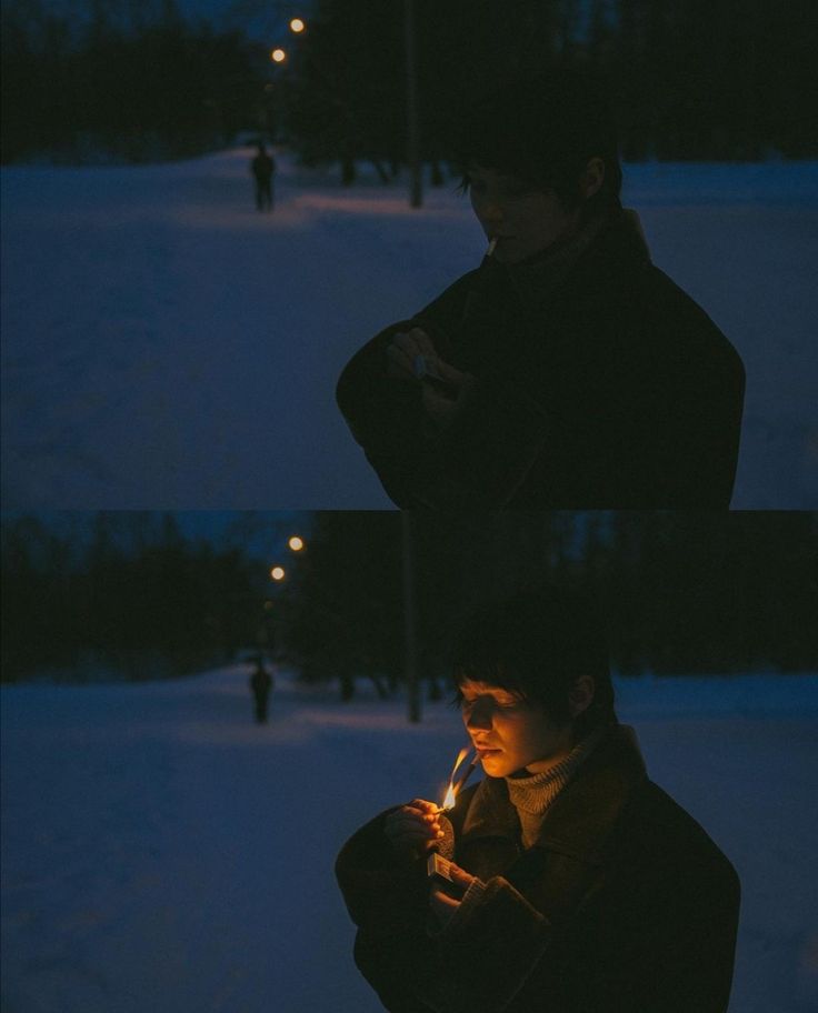 a man standing in the snow holding a lit candle