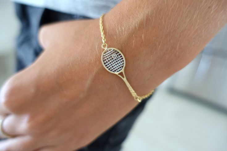 a tennis racquet bracelet on a person's wrist