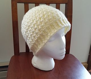 a white crocheted hat sitting on top of a wooden chair