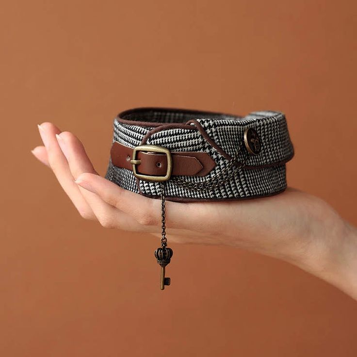 a woman's hand holding a brown and white belt with a cross on it