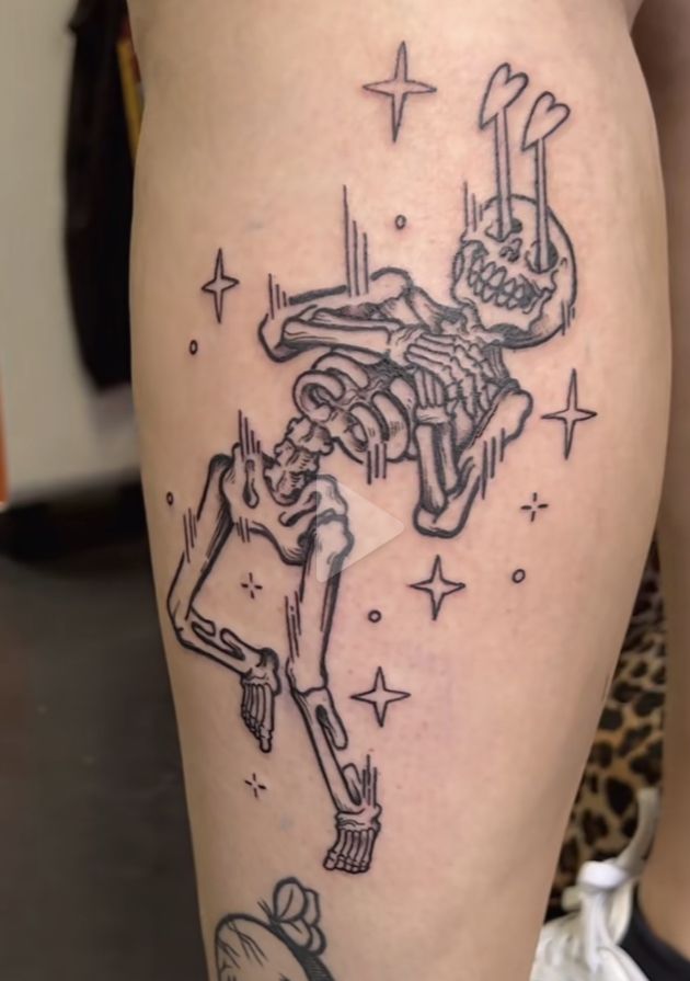 a woman's thigh with a skeleton tattoo on it and stars around her legs