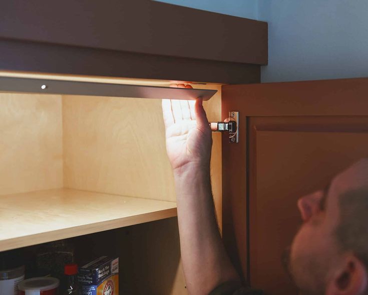 a man is opening the cabinet door to look at something on the shelf in front of him