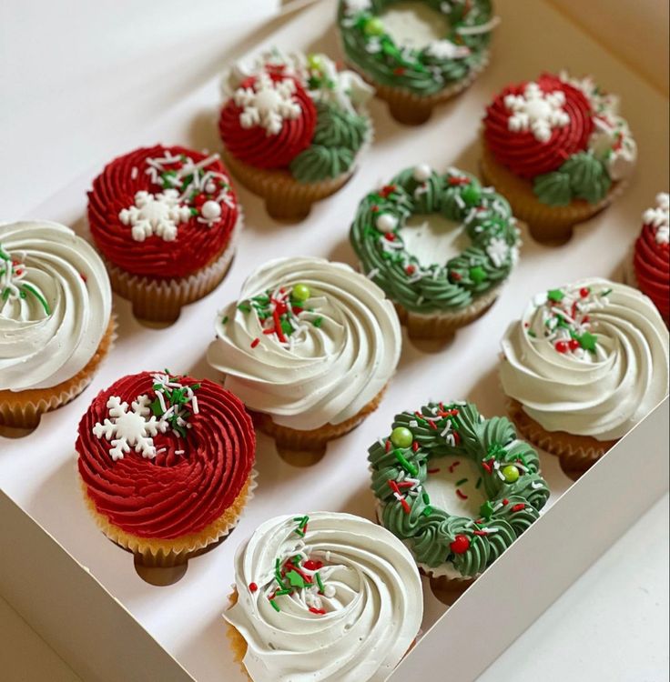 twelve decorated cupcakes in a white box