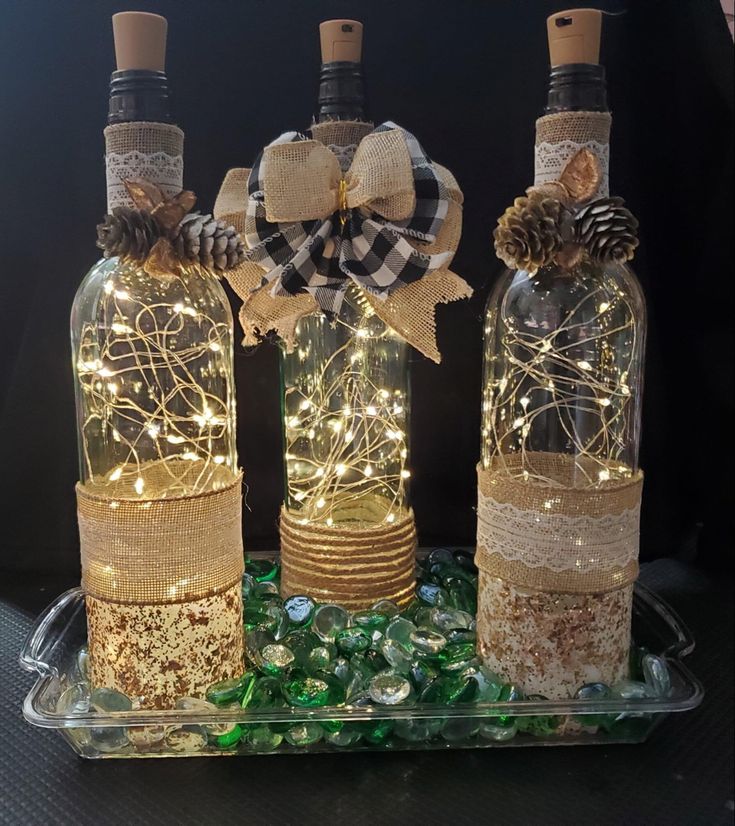 two wine bottles with lights in them on a tray