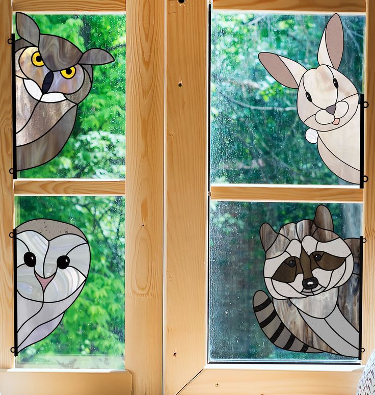 three stained glass windows with animals on them in front of a window sill and trees