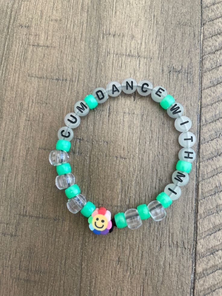 a beaded bracelet with the words cum dance and smiley face beads on it, sitting on a wooden surface