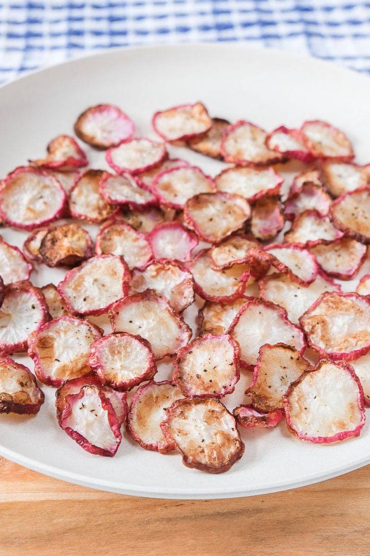 a white plate topped with sliced radishes on top of a wooden table