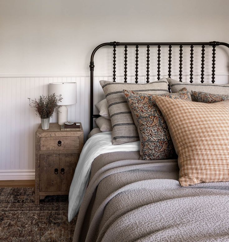 a bed with white linens and pillows in a bedroom next to a wooden table