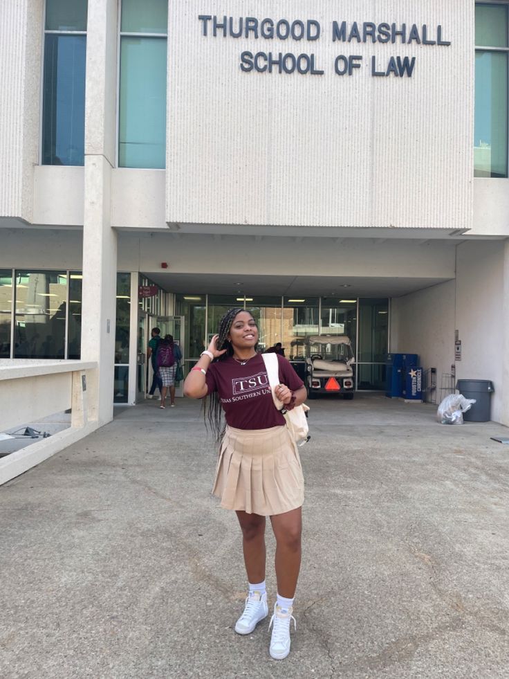 a woman standing in front of a building holding a piece of paper with the words thurgod marshall school of law on it