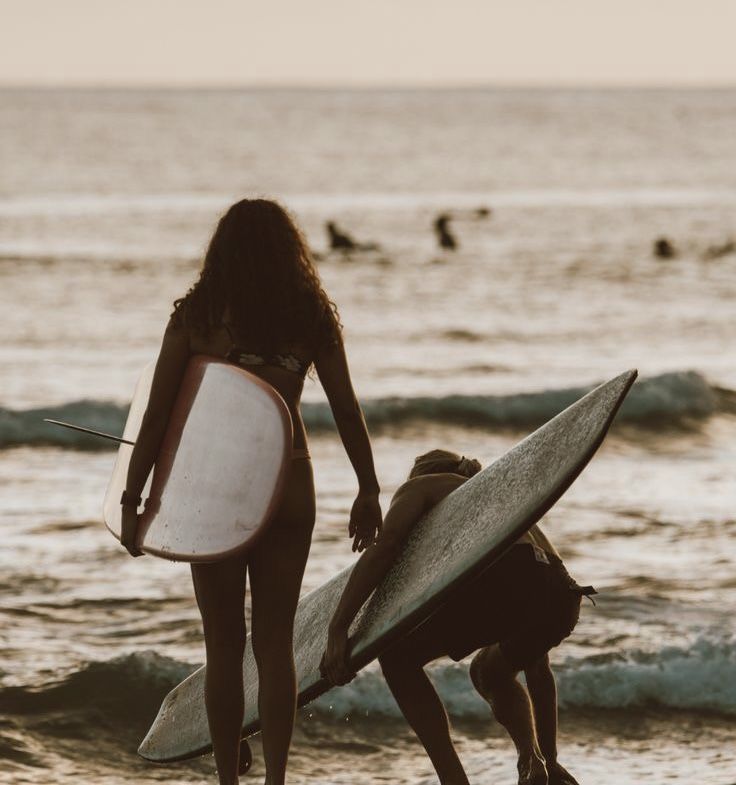 two people with surfboards are on the beach