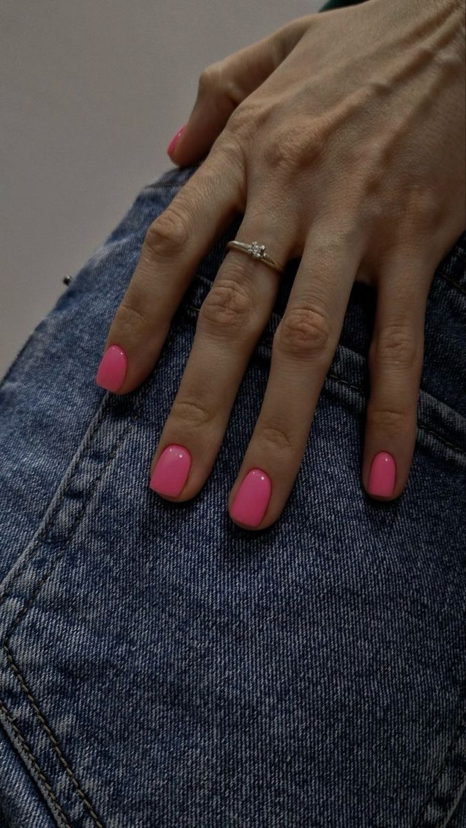 a woman's hand with pink nail polish on her nails and jeans, showing the bottom