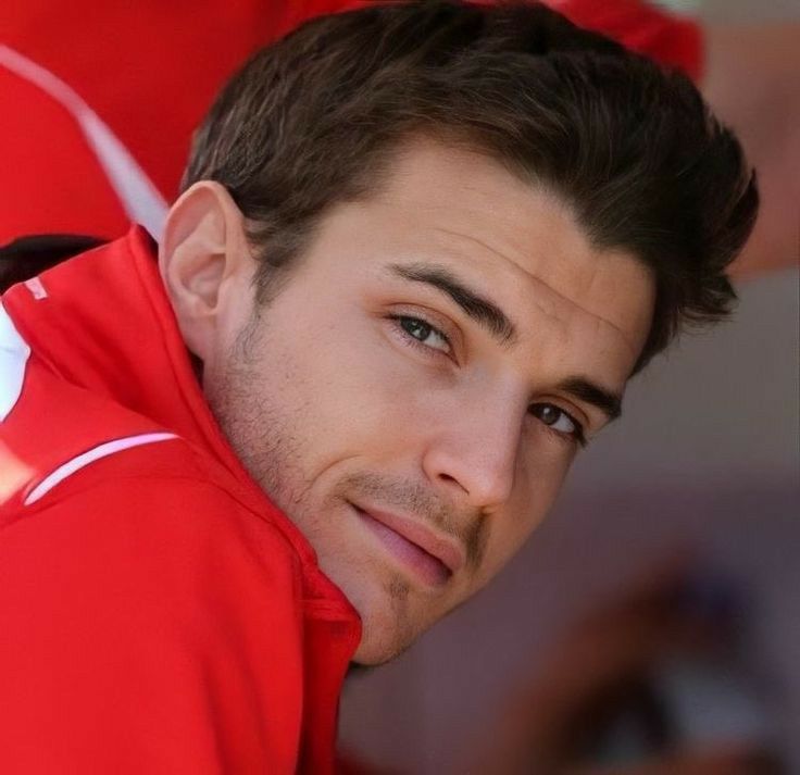 a close up of a person wearing a red jacket and looking at the camera with a serious look on his face