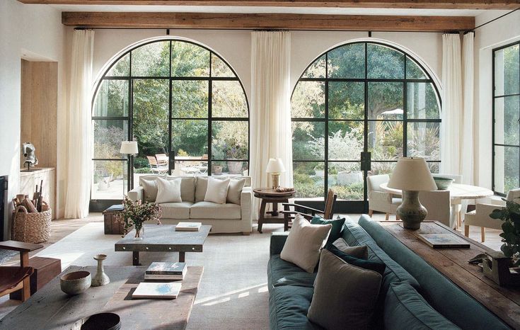 a living room filled with lots of furniture and large arched windows above the couches