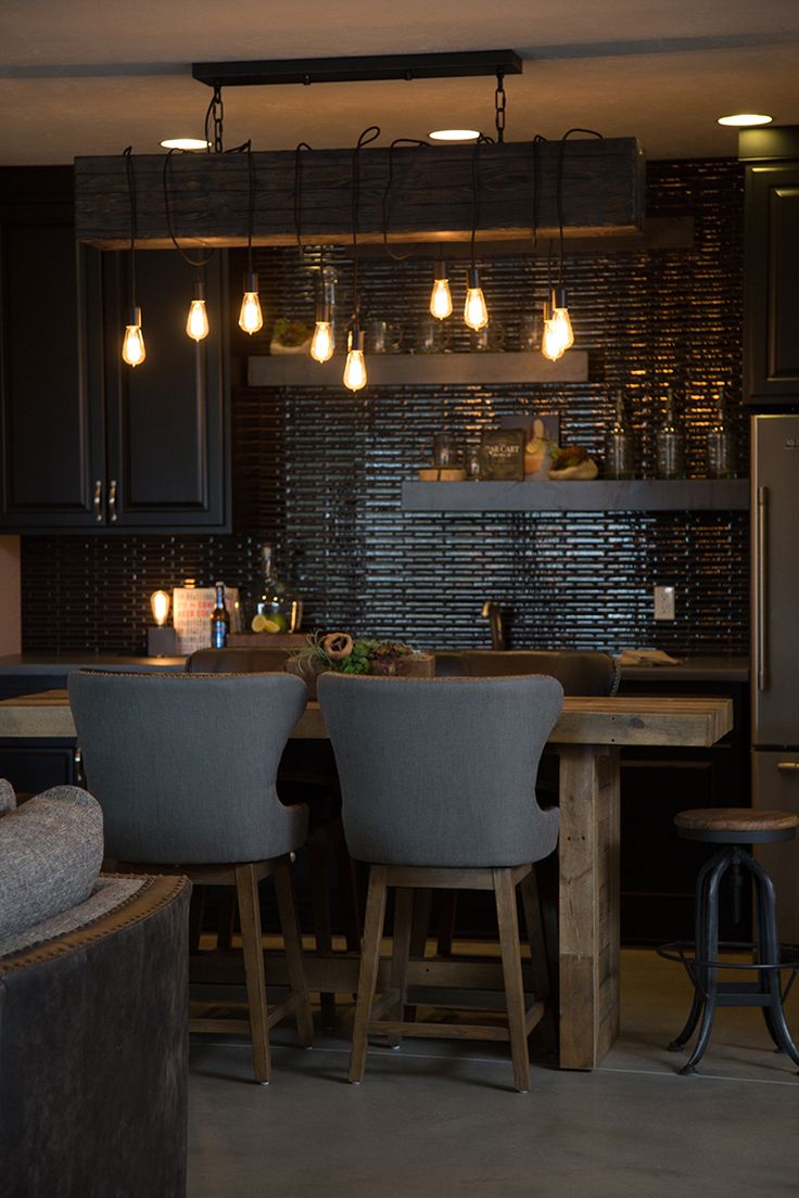 the lights are on above the kitchen table and bar stools in the middle of the room