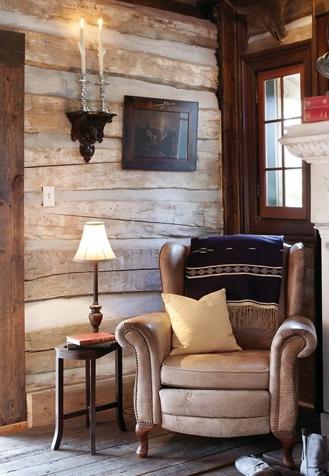 a chair sitting in front of a fire place next to a lamp on a table