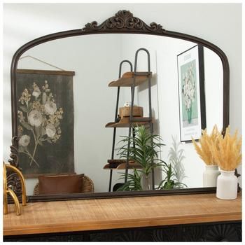 a mirror sitting on top of a wooden table next to a vase with flowers in it