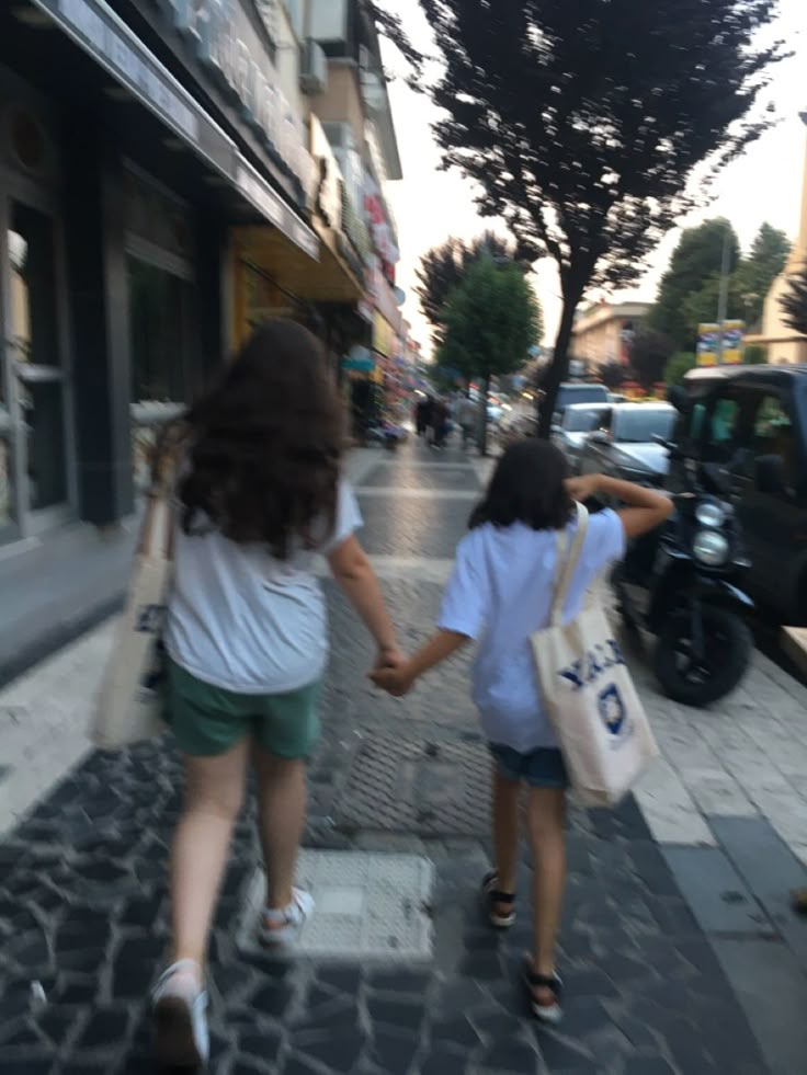 two girls walking down the street holding hands