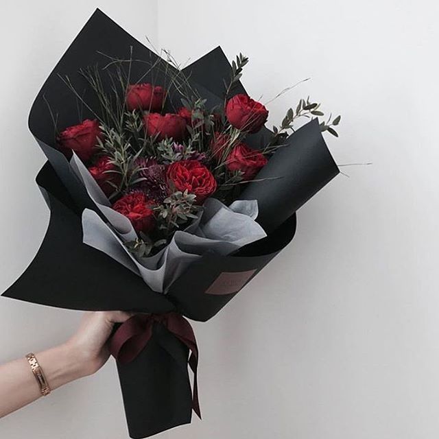 a person holding a bouquet of red roses in their left hand and wearing a bracelet