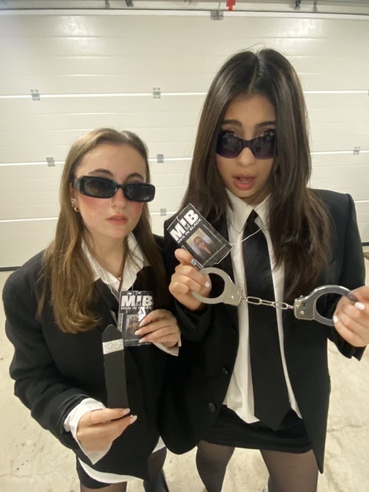 two women in business attire holding up handcuffs and book covers while standing next to each other