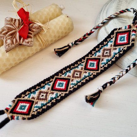 two pieces of beaded fabric next to a roll of thread and a glass bottle