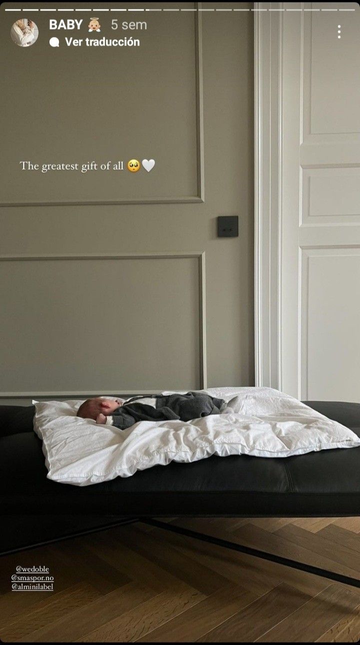 a baby is laying on top of a black bed in a room with white walls