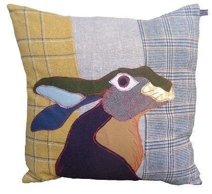 a decorative pillow with a rabbit on it's side and plaid fabric behind the cushion