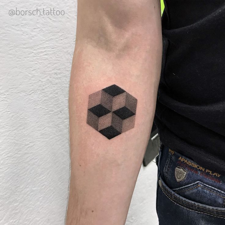 a man with a tattoo on his arm has a black and white cube design on it