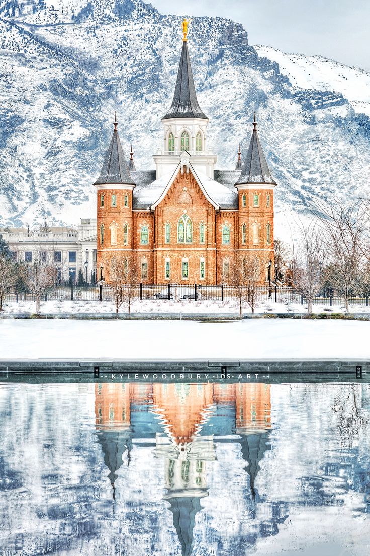 a large building with a clock tower on it's side and snow covered mountains in the background