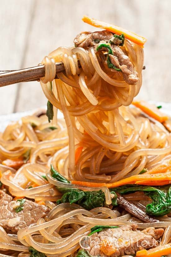 the noodles are being lifted with chopsticks from the bowl to be eaten by someone