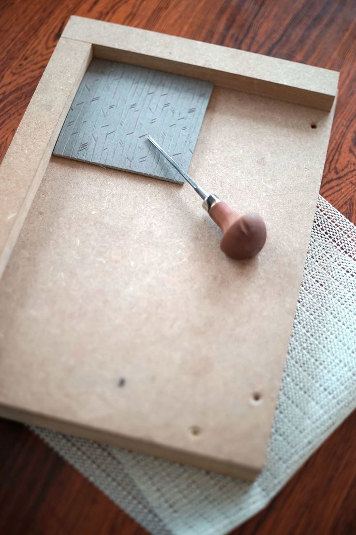 a piece of cardboard with a needle sticking out of it on top of a table