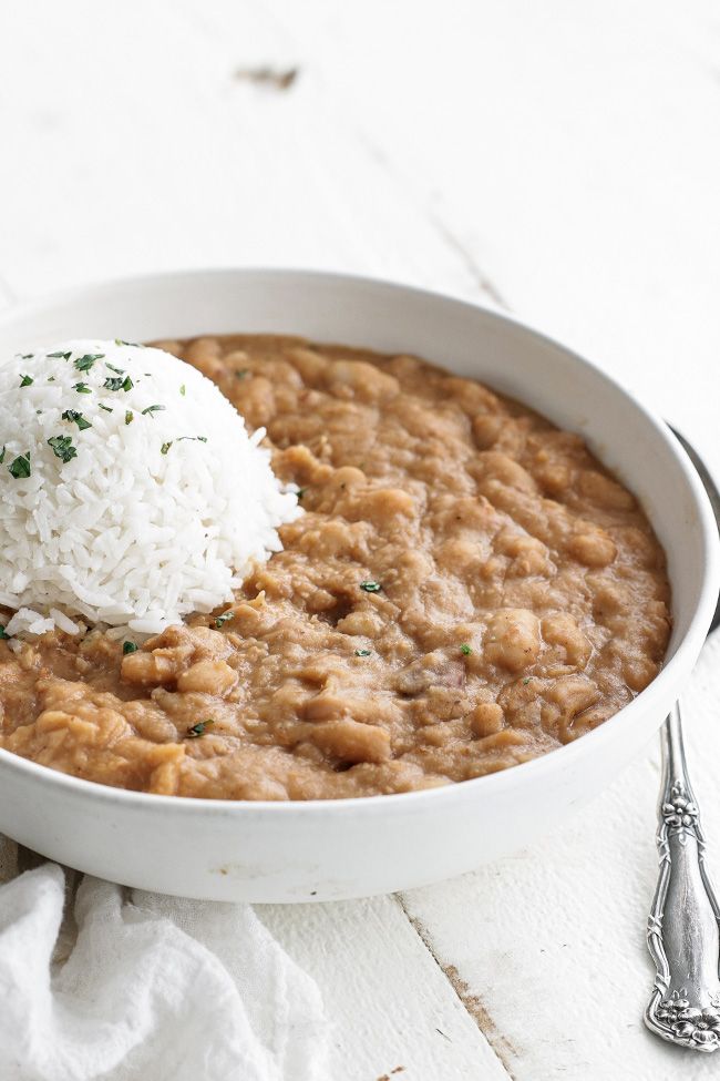 a white bowl filled with rice and beans on top of a table next to silverware