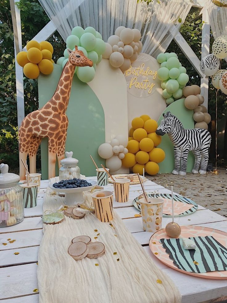 a giraffe and zebra themed birthday party with desserts on a table in front of a backdrop