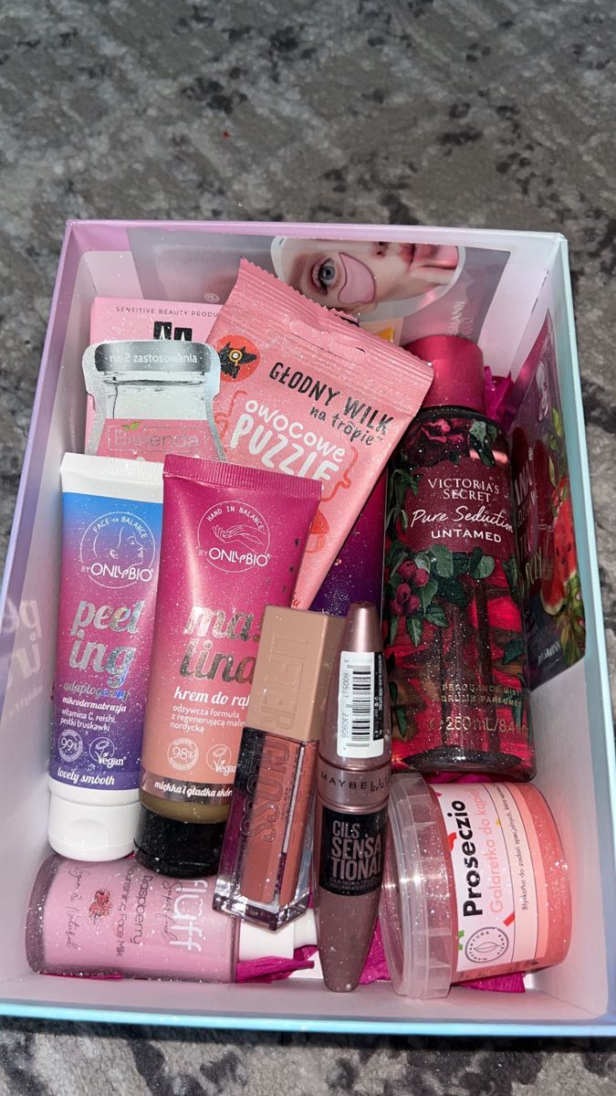 an open box containing various beauty products on a marble counter top with a baby doll in the background