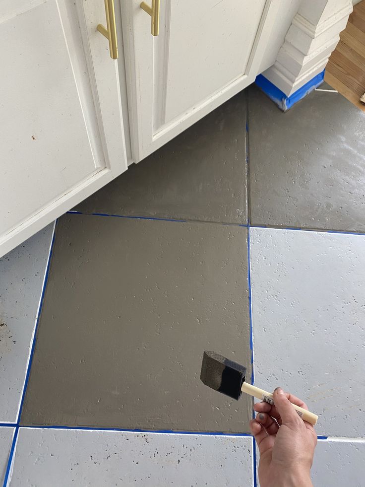 a person using a brush to paint a kitchen floor