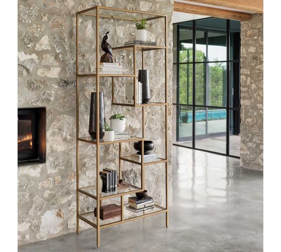 a room with stone walls and a fireplace in the center, surrounded by bookshelves