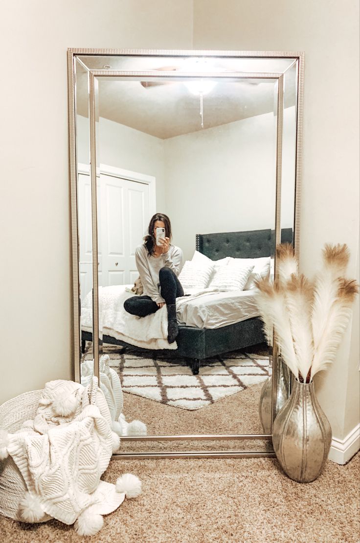 a woman sitting on a bed in front of a large mirror