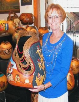 a woman is holding a decorative item in front of some pumpkins and other decorations