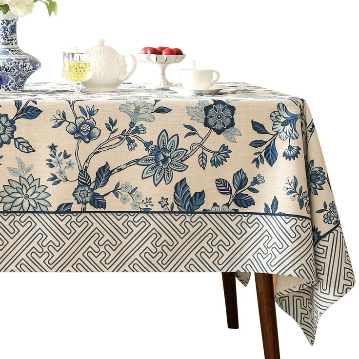 a blue and white table cloth with flowers on it, next to two vases