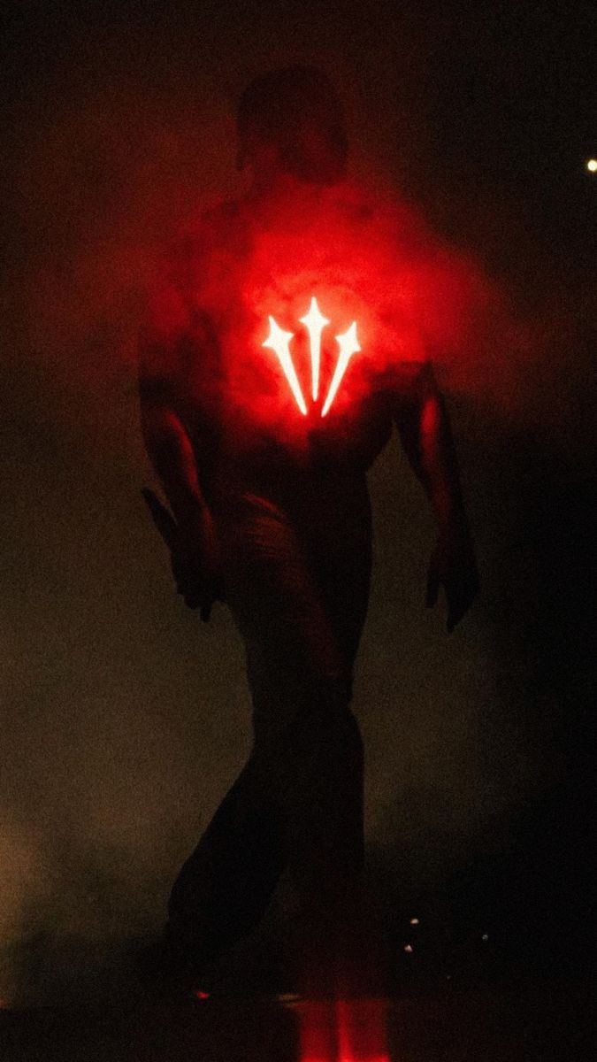 a man is standing in the dark with his hands on his hips and glowing red