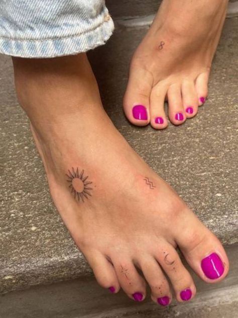 a woman's feet with pink nail polishes and a sun tattoo on her left foot