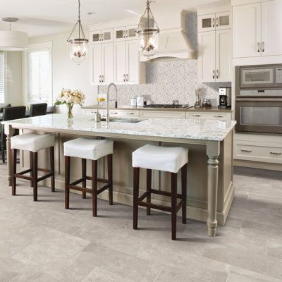 a large kitchen with white cabinets and marble counter tops, along with bar stools