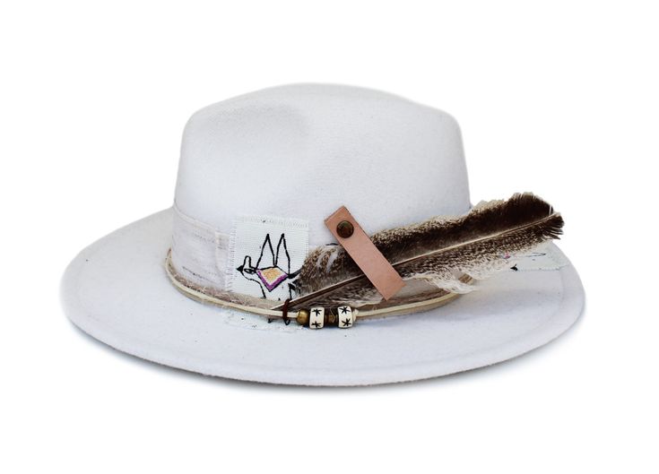 "The Mojave Hat part of the Tucson Collection Type: Center Dent Wide Brim Fedora Adjustable Size: With a tie of a knot, adjust the fit of your hat to the ideal size from 21 ¼ to 23 ¼ inches. Dimensions: Wired Brim: 2 7/8\", Crown: 4\" Color: White Materials: 65% Cotton , 35% Polyester Textured Hat bands Natural Turkey Feather Leather Strap Custom Scout Dunbar Bird Illustrations Origin: All of our hats begin in Ecuador as the body is molded, then completed at our studio in Tucson, AZ. Here we sha Whimsical Drawings, White Fedora, Bird Illustrations, Ithaca Ny, Hat Bands, Womens Fedora, Wide Brim Fedora, Felt Fedora, Sonoran Desert