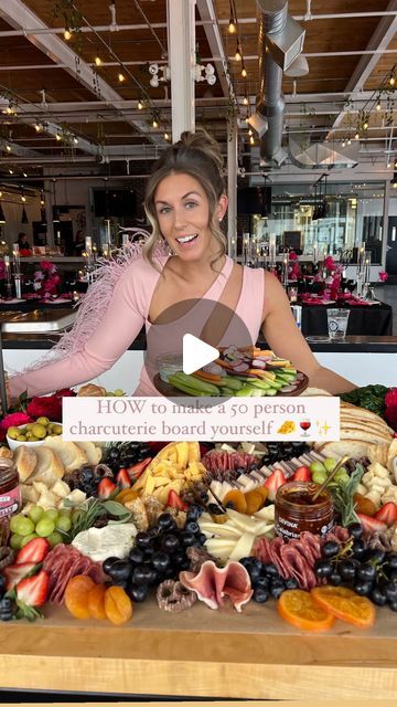 a woman standing in front of a table full of fruit and veggie platters