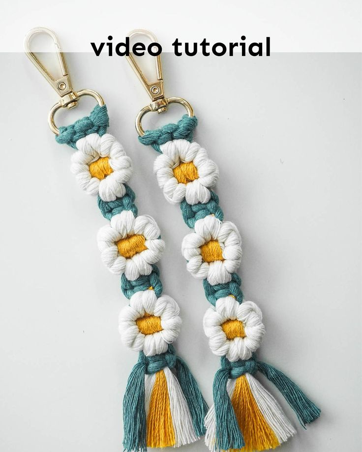 two white and yellow tasselled keychais with flowers on each side, one is