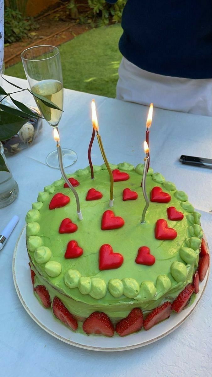 a green cake with red hearts on it and two candles sticking out of the top