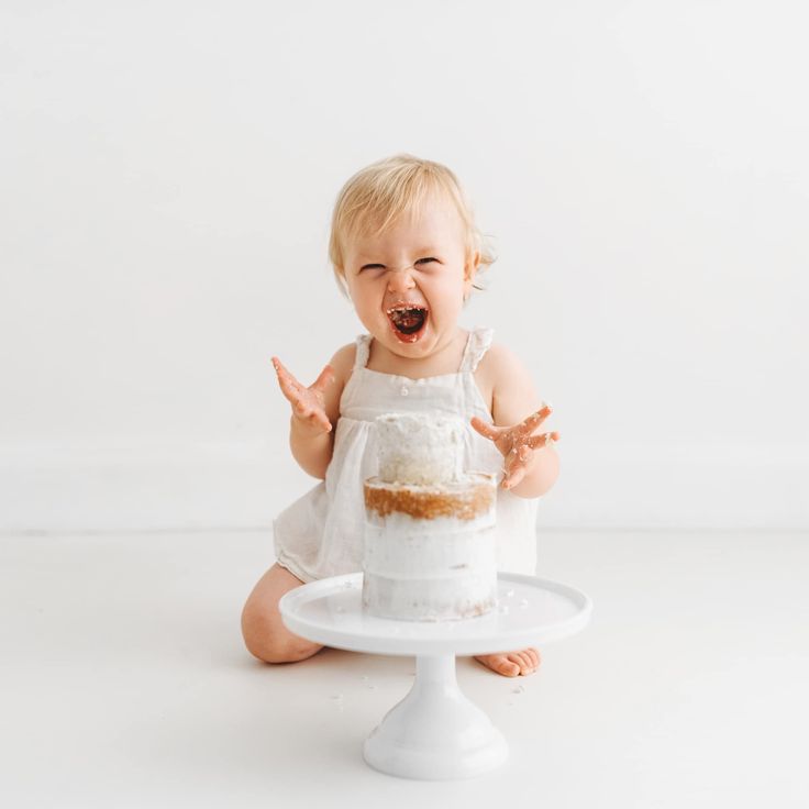 a baby sitting on the floor with a cake in front of her